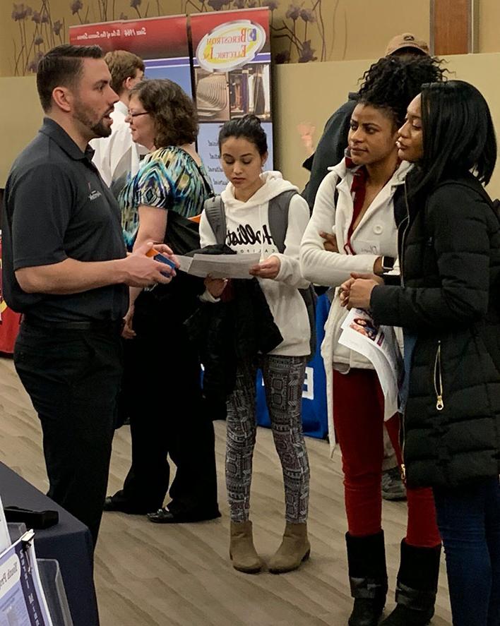 An employer talks with M State students at a job fair