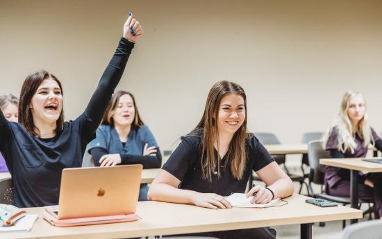 a group of students in a classroom raising their hands